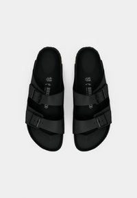 Une paire de sandales Birkenstock noires avec deux sangles réglables à boucle, taille 45, sur un fond blanc uni.