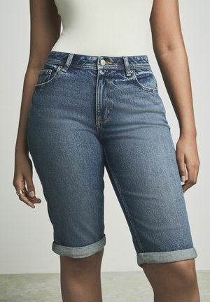 Denimbermuda shorts i medelblått, med en klassisk femfickdesign, rullade fållar och en knappstängning i midjan.