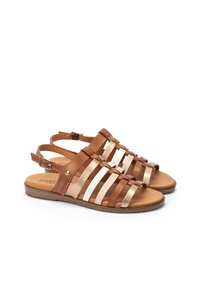 Sandalias de cuero marrón con tiras blancas y doradas, diseño de punta abierta, correa de tobillo ajustable y suela plana color tostado con un acabado texturizado.