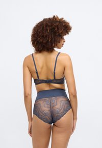 Ensemble de lingerie en dentelle marine comprenant une culotte taille haute transparente à bords festonnés et un bralette assorti avec des bretelles réglables et une fermeture à crochet.