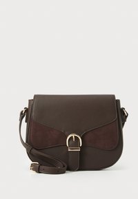 Sac en cuir marron avec un accent en suède, rabat incurvé, quincaillerie dorée, bandoulière ajustable et un détail de fermeture unique.