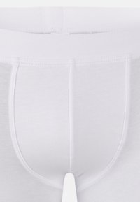 Vita bomullsunderkläder med en mjuk, elastisk midjeband. De har en slät yta och en enkel, sömlös design utan mönster.