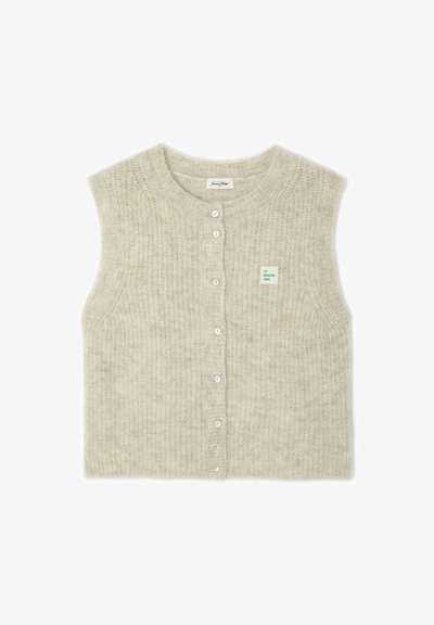 Gilet beige en tricot sans manches boutonné, col rond et petite étiquette verte indiquant "LA MAISON AMV" sur la poitrine gauche.