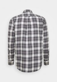 Camisa de manga larga a cuadros en gris, blanco y negro. Presenta puños con botones y cuello clásico. Tejido suave con un patrón de cuadros.