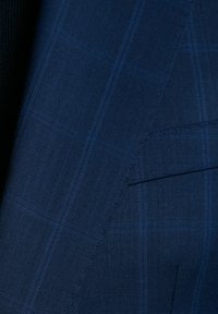 Granatowa wełniana tkanina z subtelnym wzorem w kratę, zawierającym jaśniejsze niebieskie linie, gładką teksturę i widoczne detale szycia.