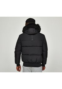 Czarna pikowana kurtka typu puffer z dużym kołnierzem z sztucznego futra, wyściełana, z prążkowanymi mankietami i dołem oraz centralnym paskiem z tyłu.