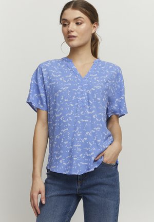 Blusa corta de manga corta azul con escote en V y un sutil estampado en toda la prenda, confeccionada en una tela ligera. Presenta un corte relajado y aberturas laterales.