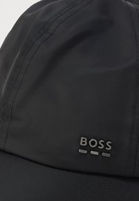 Black fabric cap with visible stitching and a small metallic "BOSS" logo on the front panel.