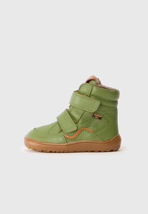 Chaussure enfant montante en cuir vert avec deux bandes Velcro, semelle marron, accent orange et doublure en polaire visible au col.