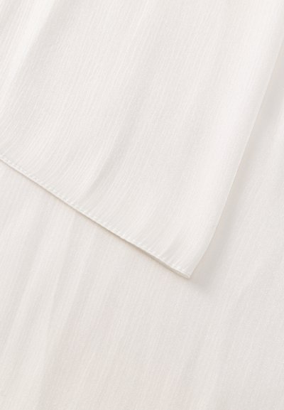 Gros plan sur des panneaux de tissu blanc superposés avec une texture subtile et des bords cousus.