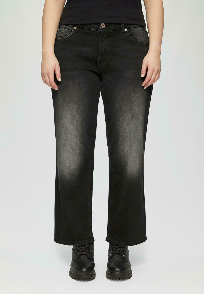 Zwarte denim wijde pijpen broek met een vervaagde afwerking, vijf zakken en zilveren hardware. G gedragen met zwarte veterschoenen.