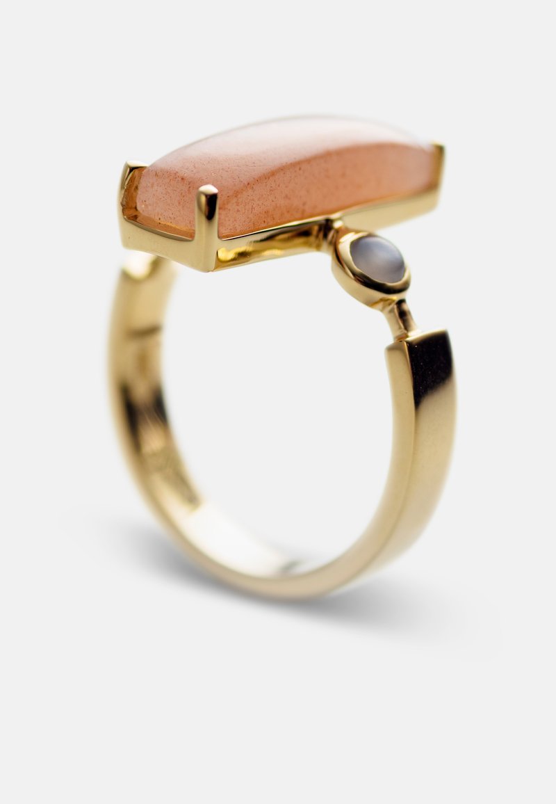 Goldring mit einem rechteckigen Pfirsichstein und einem kleineren ovalen Akzentstein. Glatte, polierte Oberflächen und ein schlankes, modernes Design.