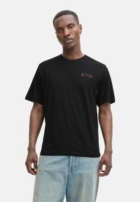 Sort bomulds t-shirt med en lille rød "KYOTO JAPAN" tekst på venstre bryst, korte ærmer og en afslappet pasform.