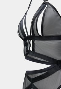 Bralette in rete nero con coppe triangolari, tessuto trasparente e fasce in satin con ritagli geometrici e dettagli per una maggiore struttura.