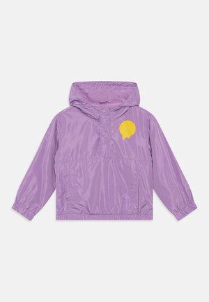 Purple windbreaker jacket with a hood, featuring a yellow smiley face logo on the chest and elastic cuffs at the sleeves. Lightweight material.