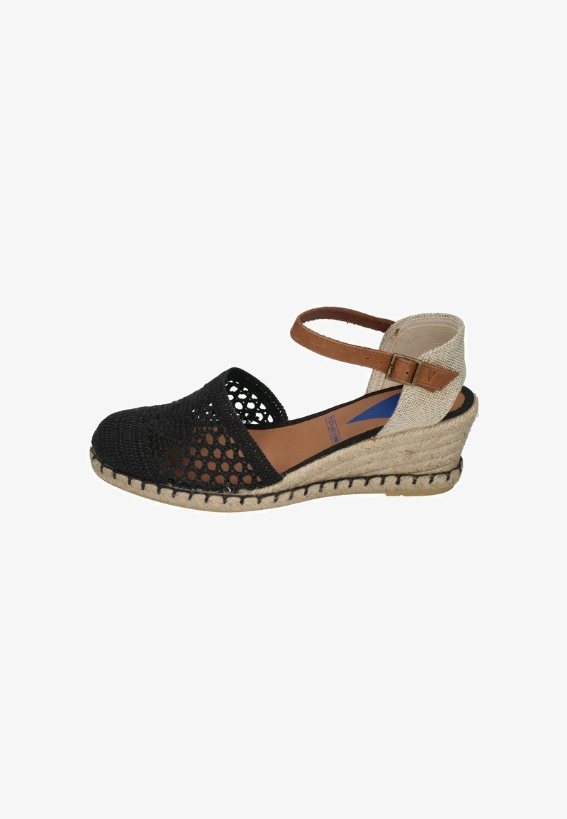 Espadrilles negras trenzadas con cuña y correa al tobillo, suela de cuerda natural y parte trasera de lienzo beige. Diseño de punta abierta y detalles de tela texturizada.