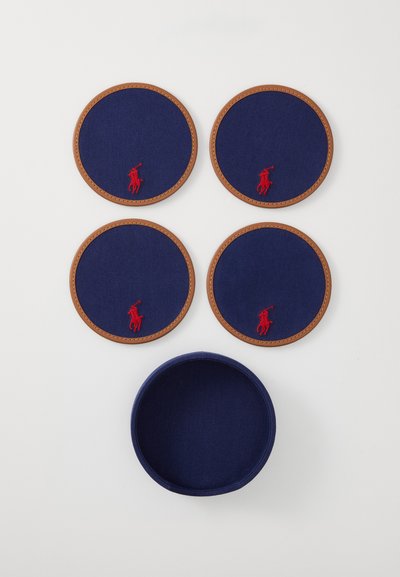 Sett med fire runde marineblå underlag med lys brune lærkanter og en rød brodert logo, ledsaget av en matchende rund oppbevaringsholder.