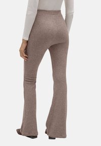 Pantalones de campana marrones acanalados con cintura alta y textura suave, que ofrecen un ajuste ceñido en los muslos y un flare relajado en el dobladillo.