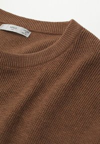 Brązowy, prążkowany sweter z dzianiny z zaokrąglonym dekoltem i subtelną fakturą. Widoczna metka z informacjami o marce i rozmiarze.