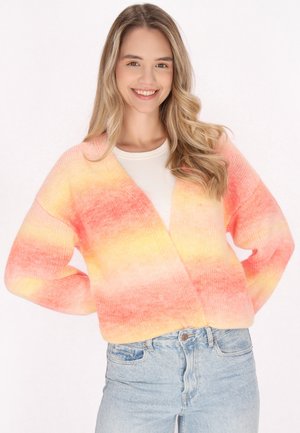 Gebreide cardigan in verloopkleuren van roze en geel, met een V-hals, losse pasvorm en lange mouwen, gecombineerd met lichtblauwe spijkerbroek.