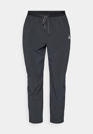 Černé lehké sportovní kalhoty s elastickým pasem, nastavitelným stahovacím šňůrkou a zipy na lemech pro přizpůsobení střihu.