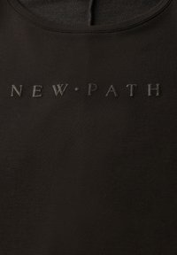 Zwart katoenmix top met een ronde halslijn, met reliëftekst "NEW·PATH" in een matte afwerking op de voorkant. Soepele textuur.