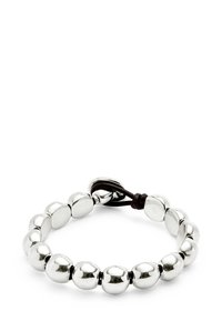 Pulsera metálica plateada con cuentas redondeadas, alternando formas suaves y ligeramente aplanadas, asegurada con un cordón marrón oscuro.