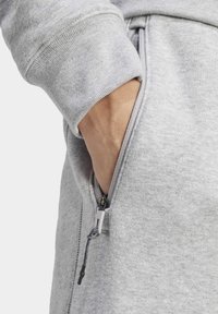 Grå sweatshirt med en dragkedjeficka, med ribbad mudd och dragsko-detalj. Mjuk tygkvalitet med synlig sömnad.