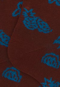 Braune Socken mit blauen Ananasmustern, die über eine glatte Textur und ein enges Design verfügen. Mit einer verstärkten Spitze für Langlebigkeit akzentuiert.