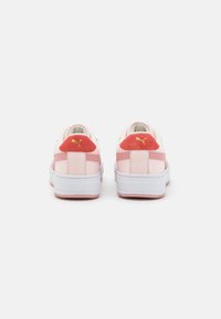 Puma sportcipők puha rózsaszín bőrrel és nubuck részletekkel, lekerekített forma, fehér középtalppal és textúrázott gumitalppal. Piros sarok részlet.