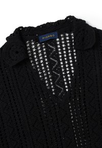 Schwarzes gehäkeltes Top mit V-Ausschnitt, das ein strukturiertes Muster, gewellte Kragendetails und ein blaues Etikett mit der Aufschrift "PIOMBO" aufweist.