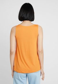 Top sin mangas naranja con escote redondo, hecho de una tela suave; presenta un corte relajado con un dobladillo ligeramente curvado.