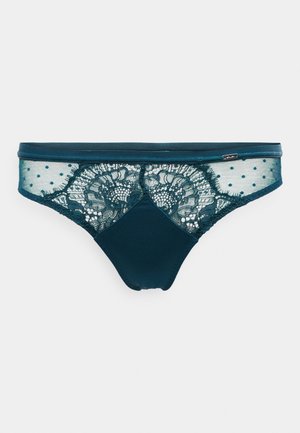 Teal lace thongi, jossa on pilkkupisteet verkko sivut, kiinteä kangas etuosassa ja monimutkainen kukkakuvioinen pitsi takana.