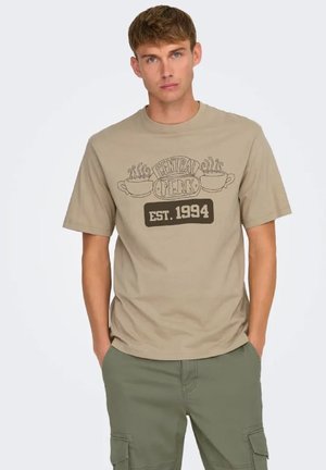 Camiseta de algodón beige con un gráfico de Central Perk en marrón que incluye dos tazas de café y el texto "EST. 1994", combinada con pantalones cortos de cargador en verde oliva.