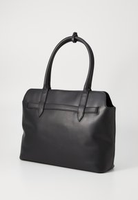 Sac fourre-tout en cuir noir avec deux poignées allongées, une bande horizontale à l'avant et une texture lisse. Forme rectangulaire avec des bords arrondis.