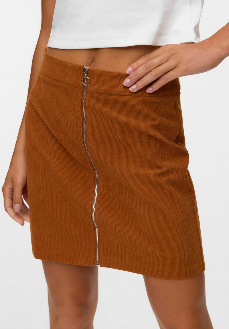 Brun kordflorts mini kjol med framzipper, med en slät yta och en subtil ribbstruktur. Zippern har ett metallhandtag.