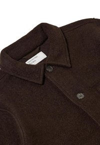 Giacca di lana marrone scuro con colletto, caratterizzata da due bottoni neri e un'etichetta con la scritta "Universal Works". Tessuto morbido e strutturato.