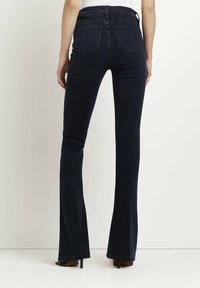 Mörkblå utsvängda jeans med hög midja, utrustade med fem fickor, synlig sömnad och ett slätt, lätt strukturerat tyg.