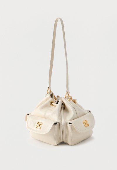 Κρεμ δερμάτινη τσάντα τύπου κουβά με μακρύ λουράκι, δύο μπροστινές τσέπες με χρυσά λογότυπα και χρυσαφένιες μεταλλικές τρύπες.