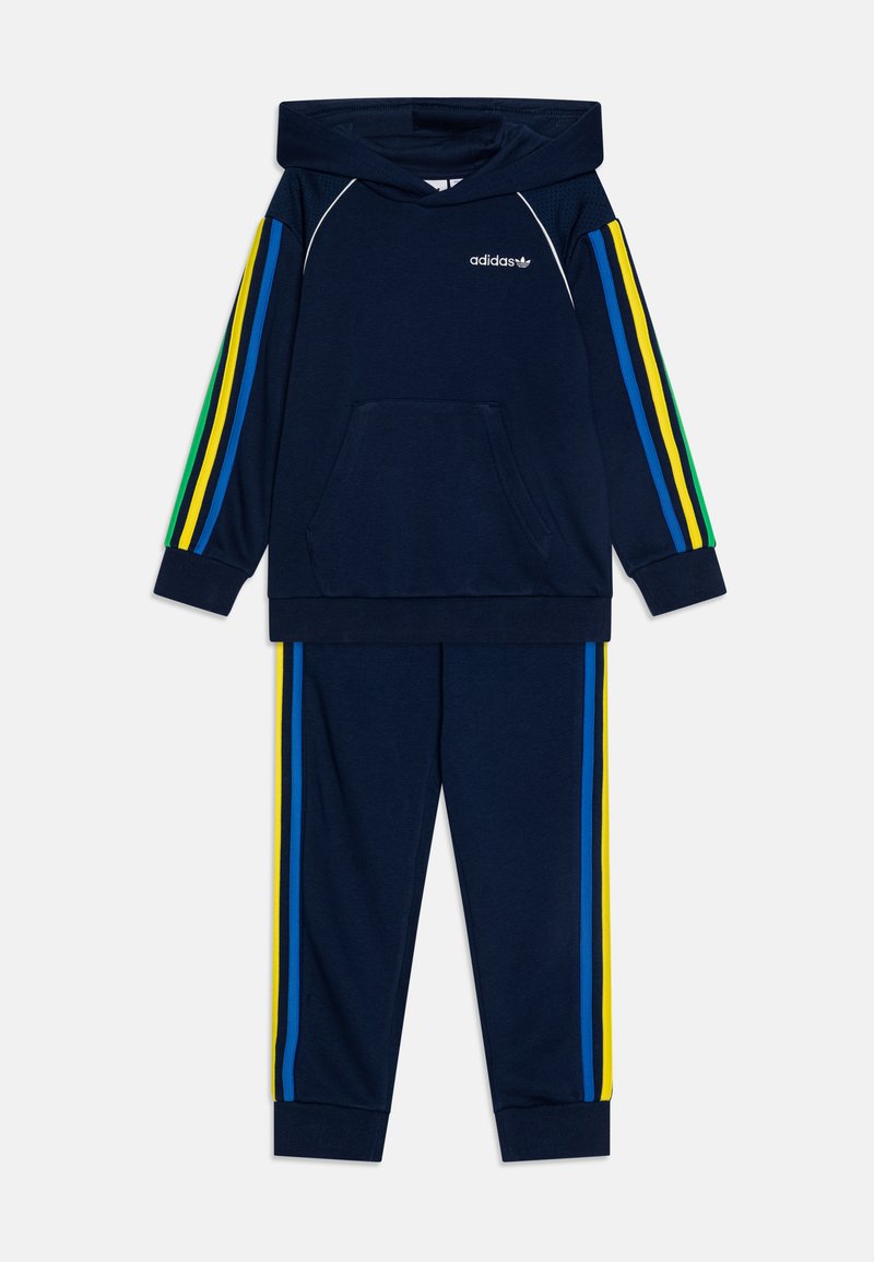 Ensemble comprenant un sweat-shirt et un pantalon bleu marine, avec des rayures latérales multicolores (vert, jaune, bleu) et une poche sur le devant du hoodie.