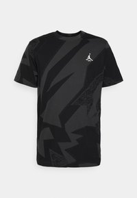 Camiseta de manga corta negra y gris oscuro con un patrón abstracto, con pequeño logo blanco de Jumpman en el lado izquierdo del pecho.