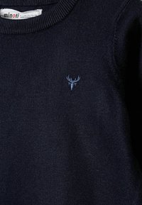 Mornarsko moder pleten pulover s okroglim izrezom. Ima majhen svetlo moder vezen jelenji logotip na levem prsnem predelu. Mehak občutek.