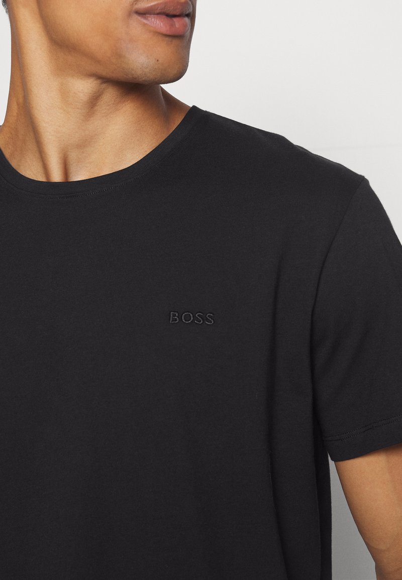 Czarny bawełniany t-shirt z okrągłym dekoltem, krótkimi rękawami oraz teksturowanym, haftowanym logo "BOSS" na piersi. Gładka tekstura materiału.