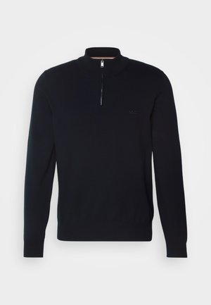 Svart stickad tröja med hög krage och halv dragkedja. Har subtil varumärkeslogotyp på bröstet samt ribbade ärmslut och fåll.