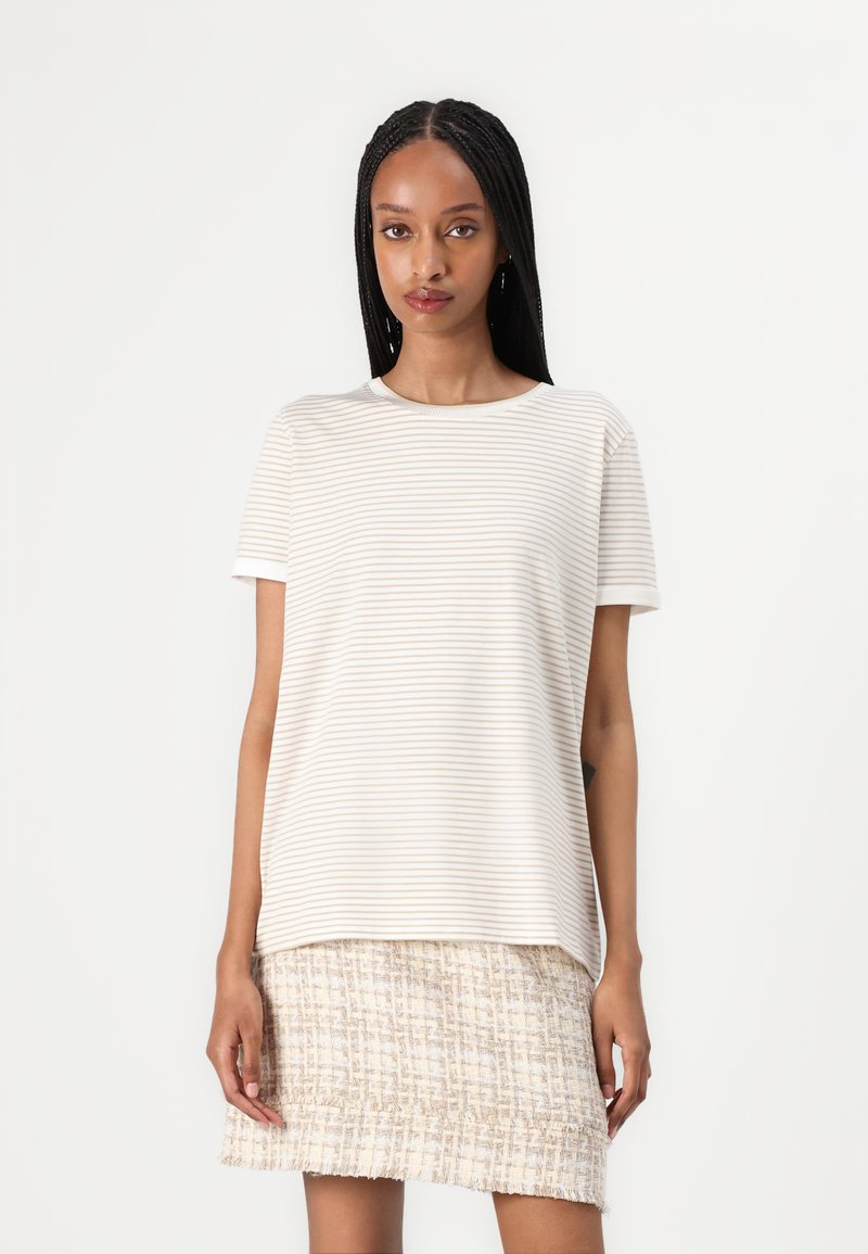 Camiseta de manga corta a rayas color crema, hecha de una tela suave, combinada con una falda clara texturizada y con flecos. Cuello redondo sencillo.