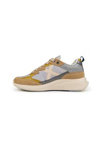 Zapatilla deportiva que presenta una combinación de ante marrón, malla gris y detalles en amarillo, con una suela gruesa color crema y un destacado logo de estrella.