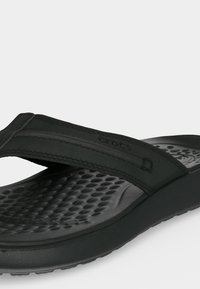 Μαύρες σαγιονάρες Crocs από αφρό με υφασμένο πάτο και επενδυμένο λουράκι στο πάνω μέρος για καθημερινή χρήση.