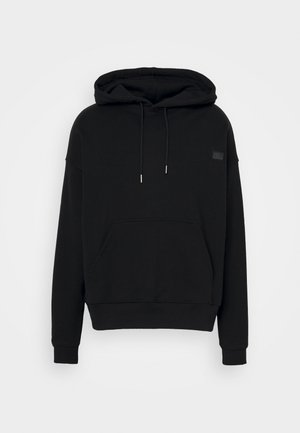 Black hooded sweatshirt made of soft fabric. Features a front pocket, drawstring hood, and a small logo patch on the chest.