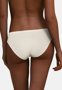 Witte katoenen hipsteronderbroek, gladde textuur, laag uitgesneden ontwerp, naadloze randen en een stijl met minimale bedekking.