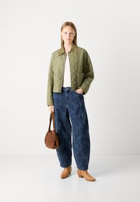 Kätkestatud oliivroheline jakk kraega, valge ülis, sinise lillemustriga laiade jalgadega teksad, pruun süsikott ja beežid nilkkingsad.